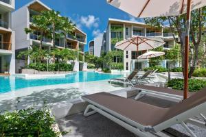 a swimming pool with two lounge chairs and an umbrella at Wyndham Grand Nai Harn Beach Phuket in Nai Harn Beach