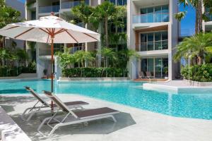 a swimming pool with a beach chair and an umbrella at Wyndham Grand Nai Harn Beach Phuket in Nai Harn Beach