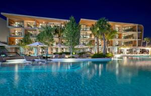 a swimming pool in front of a hotel at night at Wyndham Grand Nai Harn Beach Phuket in Nai Harn Beach