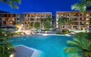 a swimming pool in front of a hotel at night at Wyndham Grand Nai Harn Beach Phuket in Nai Harn Beach