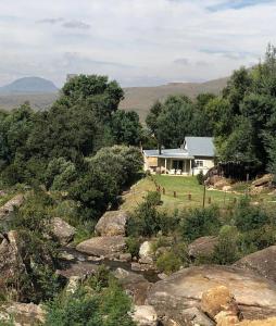 een wit huis met een rivier ervoor bij Cleopatra Mountain Farmhouse in Fort Nottingham