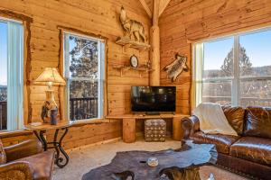 a living room with a couch and a tv and windows at Jiji & Toto's in Pagosa Springs