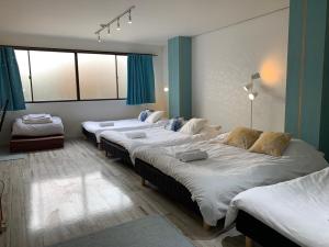 - 3 lits dans une chambre dotée de murs et de fenêtres bleus dans l'établissement Ex2 House Imamiya 202, à Osaka