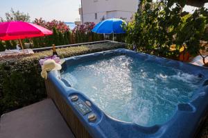 a jacuzzi tub in a backyard with umbrellas at Luton Apartment Zadar Kozino Heating Pool & Jacuzzi in Kožino