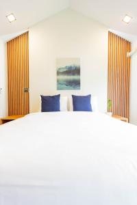 1 dormitorio con 1 cama blanca grande con almohadas azules en in My place cafotel, en Khlong Thom
