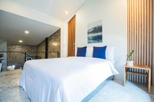 a bedroom with a large white bed with blue pillows at in My place cafotel in Khlong Thom