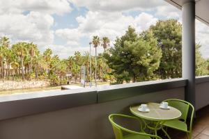 une table et des chaises dans une chambre avec une grande fenêtre dans l'établissement Aparthotel Wellness, à Paterna