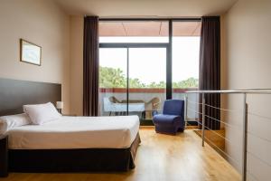 
a hotel room with a bed, chair and a window at Aparthotel Wellness in Paterna
