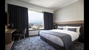 ベイルートにあるHotel De Villeのベッド、デスク、窓が備わるホテルルームです。