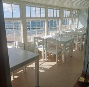 un comedor con mesas, sillas y ventanas en Gustafsbergs Badhotell & Vandrarhem, en Uddevalla