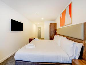 um quarto com uma cama branca e uma televisão em OYO Plymouth Central Hotel em Plymouth