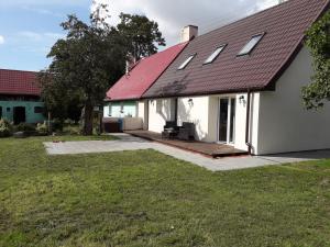 a white house with a red roof and a yard at Dom Nad Jeziorem in Wolin
