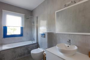 a bathroom with a sink and a toilet and a window at Anna's Villa in Mesi Village in Agia Triada