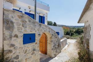 a house with a stone wall and a wooden door at Anna's Villa in Mesi Village in Agia Triada