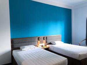 two beds in a room with a blue wall at Liberty Hotel Saigon Parkview in Ho Chi Minh City +35 photos