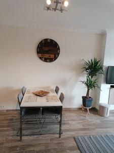 a dining room with a table and a clock on the wall at appartement oostende vlak aan zee in Ostend