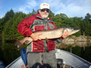 a man holding a fish in front of a boat at Tornado's Motel in Port Loring +4 photos