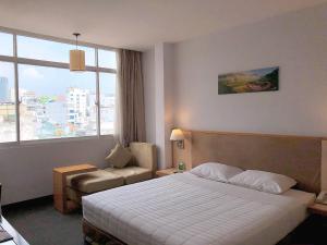 a hotel room with a bed and a chair and a window at Liberty Hotel Saigon Parkview in Ho Chi Minh City