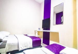 a hotel room with two beds and a mirror at Biz Hotel in Batu Pahat