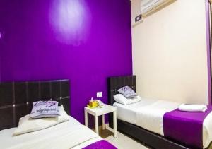 two beds in a room with purple walls at Biz Hotel in Batu Pahat