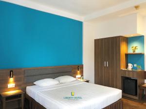 1 dormitorio con 1 cama grande y pared azul en Liberty Hotel Saigon Parkview, en Ho Chi Minh