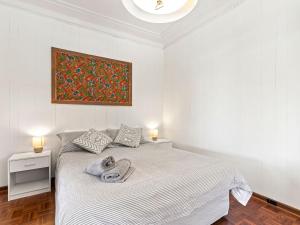 a bedroom with a white bed with a painting on the wall at Time To Unwind in Culburra Beach