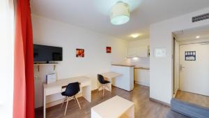 a room with a desk and chairs and a kitchen at Alezan Hôtel & Résidence in Toulouse