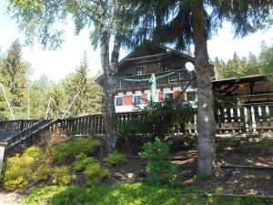 ein Haus im Wald mit einem Zaun und Bäumen in der Unterkunft Pension U Jelinka in Nové Hamry