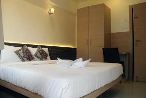 Schlafzimmer mit einem Bett mit weißer Bettwäsche und Kissen in der Unterkunft Hotel SaiPrasad Executive Solapur in Solapur