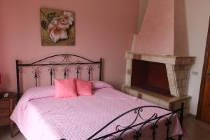 a bedroom with a bed with pink sheets and a fireplace at Sogno Salento in Guagnano