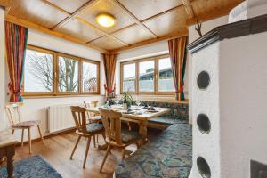 a dining room with a table and chairs and windows at Ski in - Ski out Panoramaferienhaus Breitmoos neben Mittelstation in Mittersill