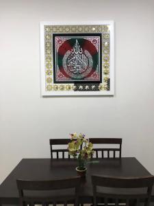a dining room table with a picture on the wall at Hasnifana Homestay Seri Iskandar in Seri Iskandar