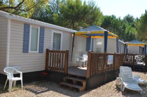Happy Camp Mobile Homes in Camping Terme Čatež في كاتيز أوب سافي: منزل مع تراس مع كراسي ومظلات