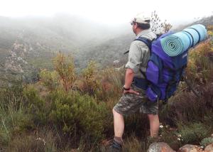 un hombre con una mochila de pie en una montaña en Eagle Falls Country Lodge & Adventures, en Buffelsdrif