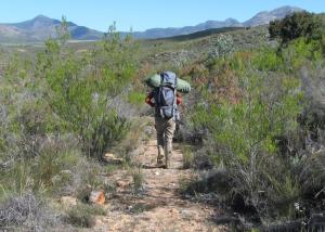 um homem andando em um trilho com uma mochila em Eagle Falls Country Lodge & Adventures em Buffelsdrif