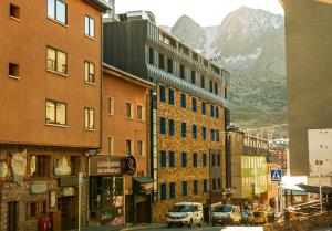 a city street with buildings and a mountain in the background at Kione Calgary in Pas de la Casa