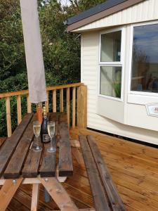 una mesa de madera con 2 copas de vino en una terraza en Captivating 2-Bed static caravan in Holyhead en Llanfachraeth