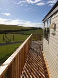 een houten terras op een huis met uitzicht op een veld bij Captivating 2-Bed static caravan in Holyhead in Llanfachraeth