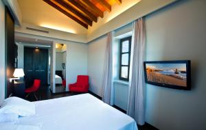 a hotel room with a bed and a tv on a wall at Hotel El Raset in Denia