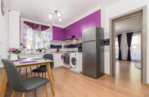 a kitchen with purple walls and a table and chairs at Apartamente Lavender Coressi in Braşov