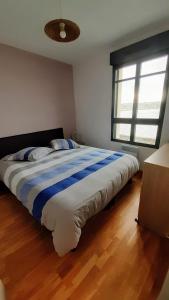 a bedroom with a bed with a blue and white striped blanket at Appartement Devant la Mer in Erquy