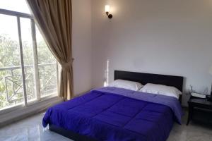 a bedroom with a bed with a purple comforter and a window at OYO 621 Home Habtoor studio's in Dubai