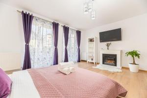 a bedroom with a bed with purple curtains and a fireplace at Apartamente Lavender Coressi in Braşov