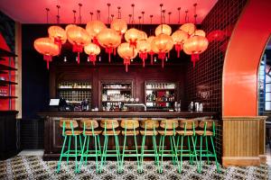a bar with green stools and red lamps at Generator Rome in Rome