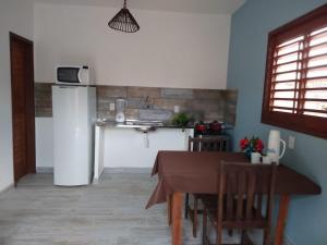 a kitchen with a table and a refrigerator at Pipa Family House in Pipa