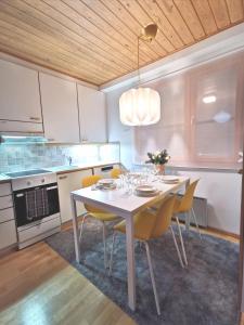 a kitchen with a white table and yellow chairs at Gold Legend Paukkula #1 - Saariselkä Apartments in Saariselka