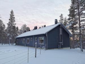 a blue house in the snow with a fence at Gold Legend Paukkula #1 - Saariselkä Apartments in Saariselka