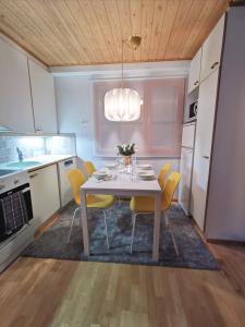 uma cozinha com uma mesa branca e cadeiras amarelas em Gold Legend Paukkula #1 - Saariselkä Apartments em Saariselka