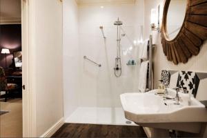 a white bathroom with a sink and a shower at The Close Hotel in Tetbury