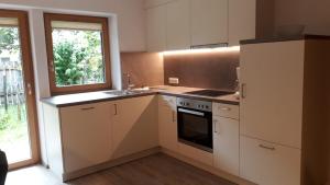 cocina con armarios blancos, fregadero y ventana en Haus Rali, en Sankt Anton am Arlberg